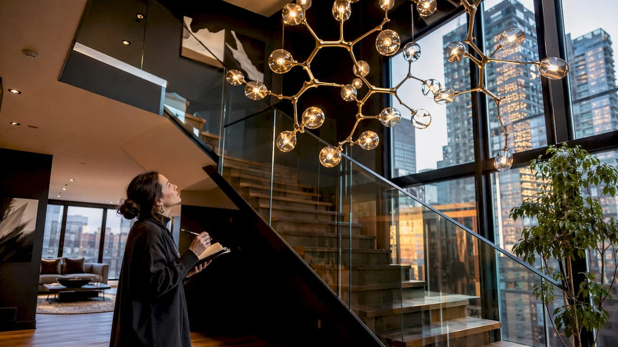 Interior designer inspecting chandelier above stairs