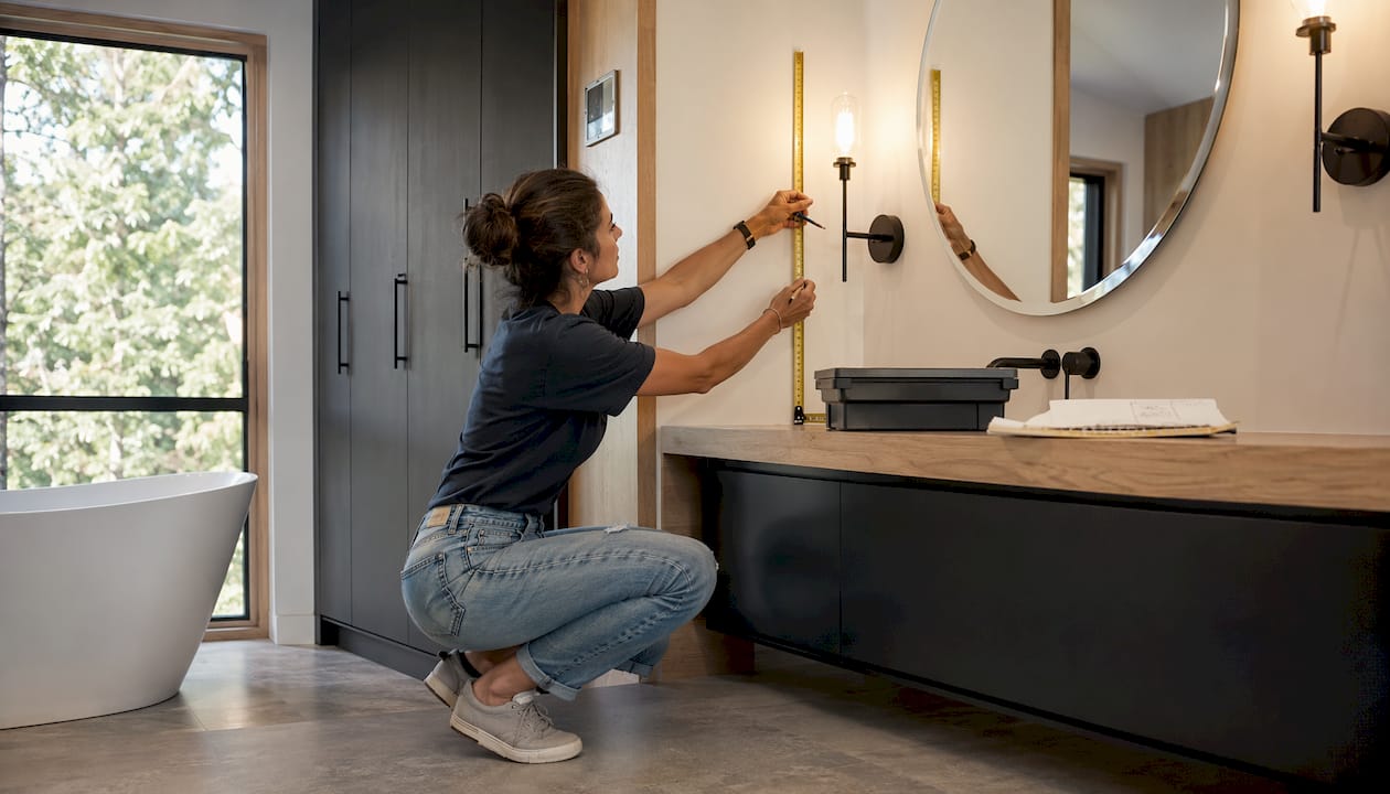 Designer measuring vanity lighting height in bathroom