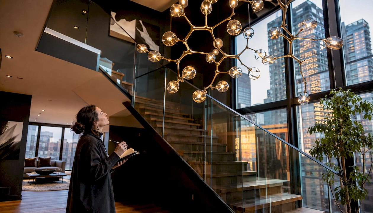 Interior designer inspecting chandelier above stairs
