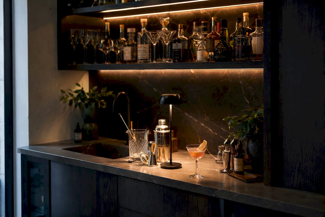 Layered warm lighting on wet bar counter with drinks