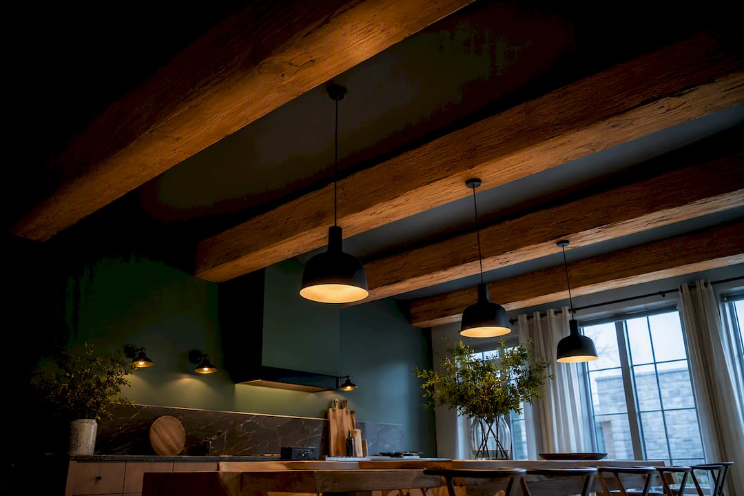 Layered lighting beneath exposed ceiling beams