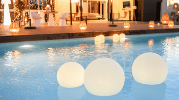 portable lights floating in a pool in a backyard