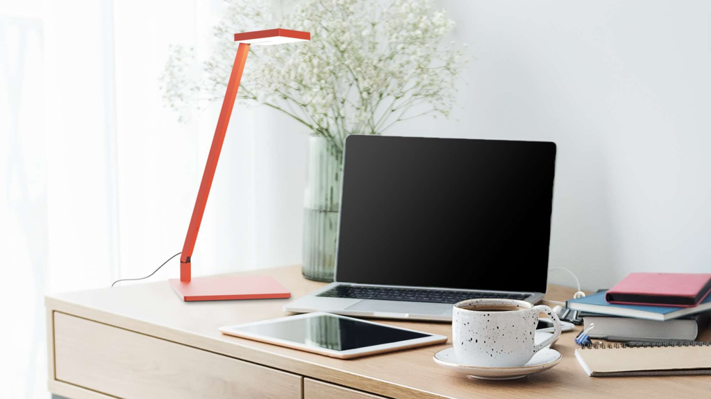 a desk with a lamp for task lighting to illuminate a laptop and ipad