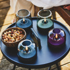 Glow 08 candle holder set with colorful glass domes and LED flames on a round tray.